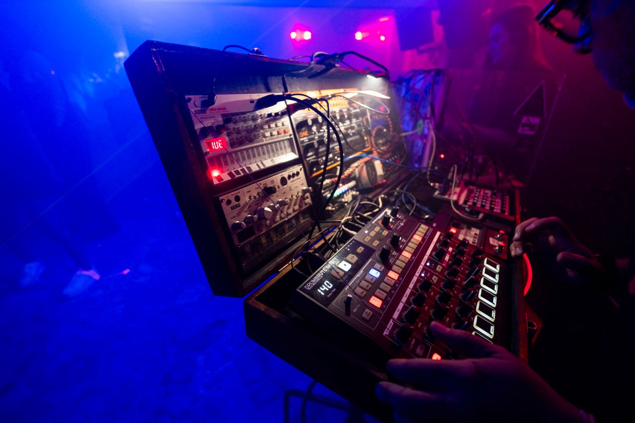 Captivating club scene with a DJ using an electronic mixing console in vibrant lighting.